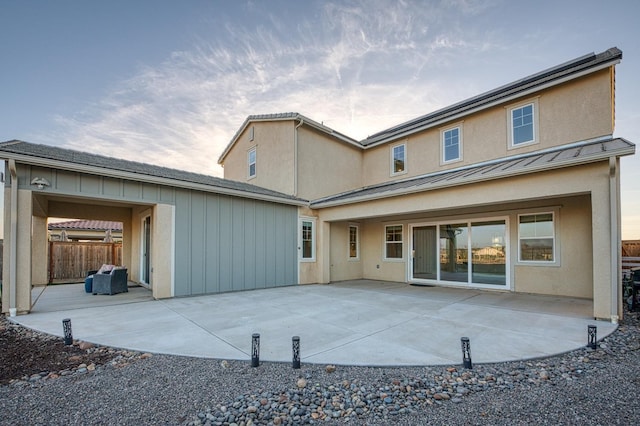 rear view of property with metal roof, a standing seam roof, fence, and a patio