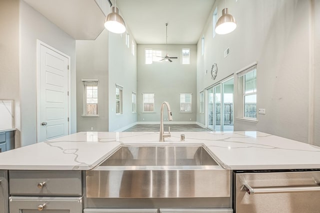 kitchen featuring stainless steel dishwasher, a healthy amount of sunlight, gray cabinetry, and a sink