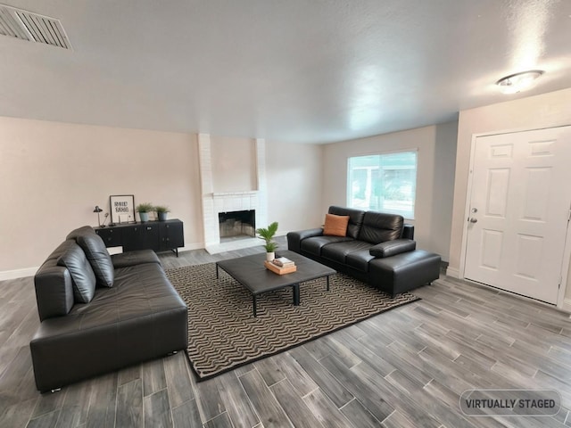 living room featuring a brick fireplace and wood-type flooring