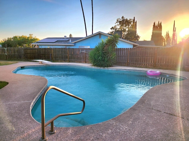 pool at dusk featuring a diving board