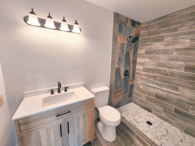 bathroom with vanity, toilet, and tiled shower