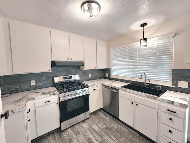 kitchen featuring stainless steel appliances, sink, decorative light fixtures, white cabinetry, and dark hardwood / wood-style flooring