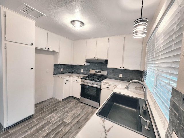 kitchen with sink, dark hardwood / wood-style flooring, hanging light fixtures, white cabinetry, and stainless steel stove