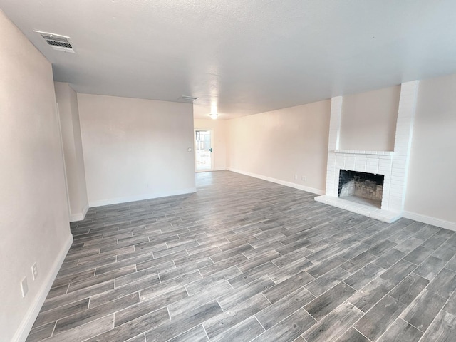 unfurnished living room with a brick fireplace and dark hardwood / wood-style flooring