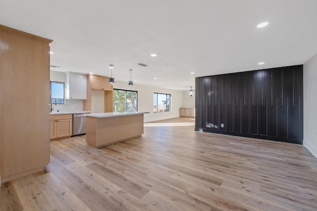 kitchen with light hardwood / wood-style floors, dishwasher, decorative light fixtures, and a kitchen island