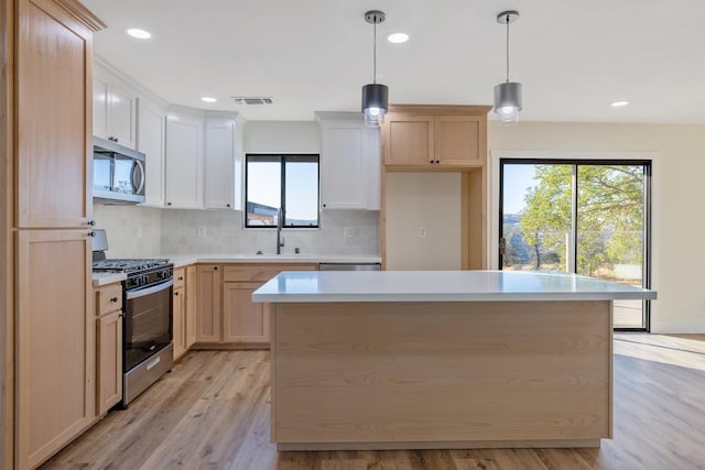 kitchen featuring light hardwood / wood-style floors, stainless steel appliances, decorative light fixtures, and a kitchen island