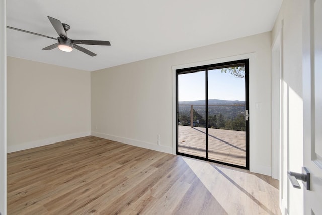 spare room featuring light hardwood / wood-style floors, a mountain view, and ceiling fan