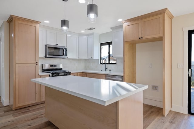 kitchen featuring hanging light fixtures, stainless steel appliances, a center island, light hardwood / wood-style floors, and tasteful backsplash