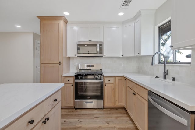 kitchen featuring sink, appliances with stainless steel finishes, light hardwood / wood-style floors, and tasteful backsplash