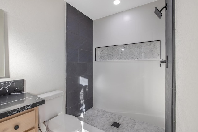 bathroom featuring vanity, toilet, and a tile shower