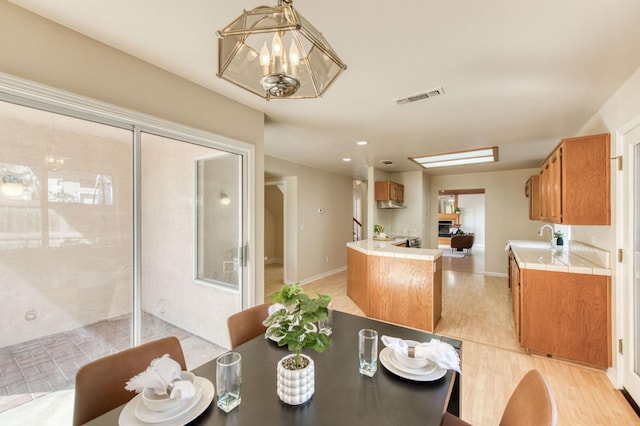 dining area with light hardwood / wood-style flooring, sink, and a notable chandelier