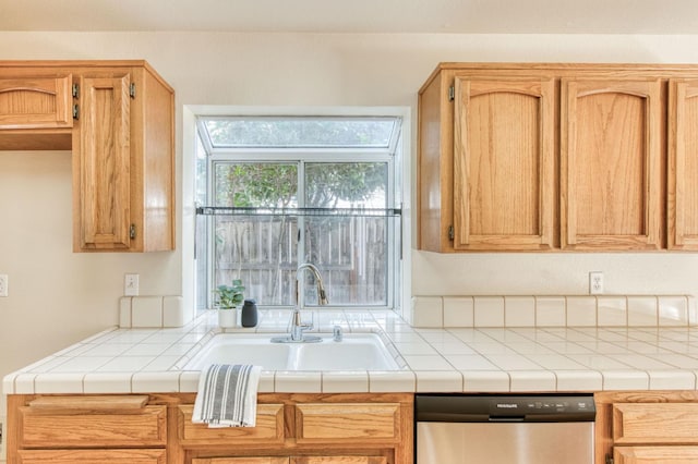 kitchen with tile countertops, dishwasher, and sink