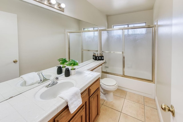 full bathroom featuring vanity, shower / bath combination with glass door, toilet, and tile patterned flooring