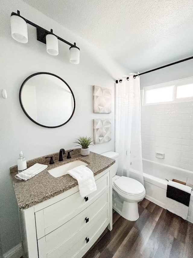 full bathroom featuring shower / bathtub combination with curtain, hardwood / wood-style floors, a textured ceiling, toilet, and vanity