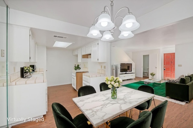49400 River Park Rd Unit 17, Oakhurst, CA 93644 - dining room with light wood-type flooring, a chandelier, and baseboards