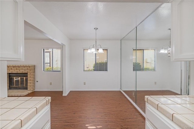 49400 River Park Rd Unit 17, Oakhurst, CA 93644 - unfurnished bedroom with a chandelier, wood finished floors, a brick fireplace, and baseboards