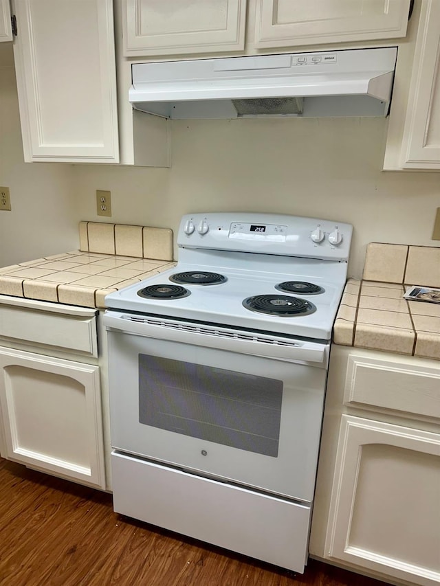 49400 River Park Rd Unit 17, Oakhurst, CA 93644 - kitchen with white electric stove, under cabinet range hood, tile countertops, white cabinets, and dark wood finished floors