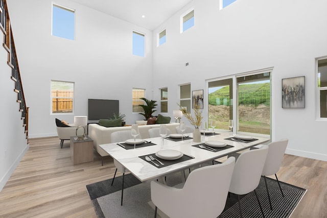 dining space featuring a towering ceiling and light hardwood / wood-style floors