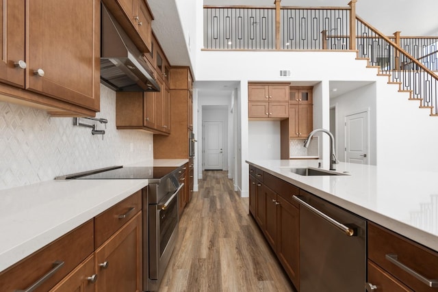 kitchen featuring wood-type flooring, sink, stainless steel appliances, decorative light fixtures, and decorative backsplash