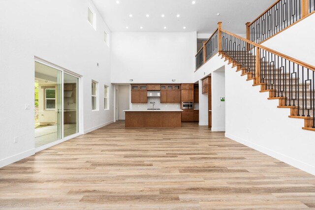 unfurnished living room featuring a high ceiling and light wood-type flooring