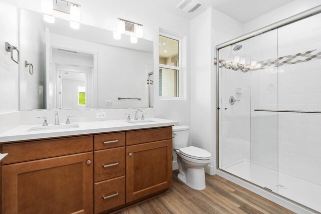 bathroom featuring a shower with door, vanity, hardwood / wood-style floors, and toilet