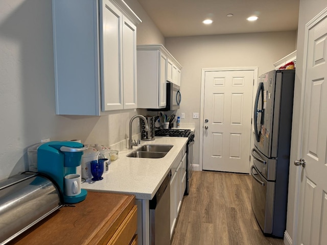 kitchen featuring appliances with stainless steel finishes, white cabinetry, sink, and hardwood / wood-style floors