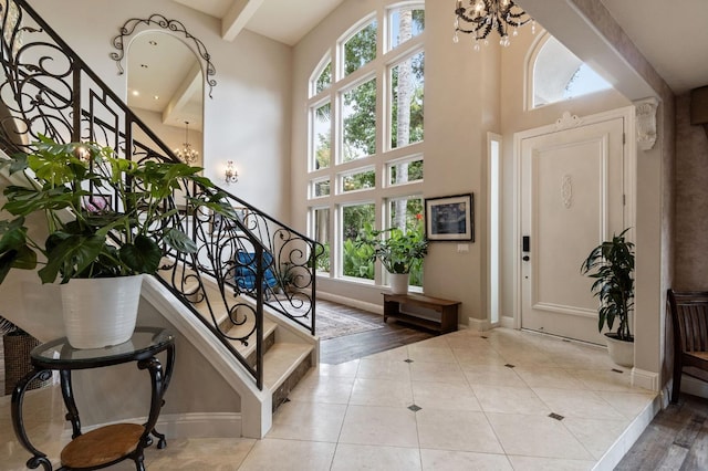 foyer featuring an inviting chandelier, a wealth of natural light, beamed ceiling, and light tile patterned floors