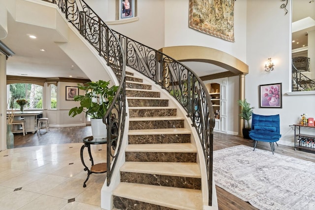 staircase with ornamental molding, a towering ceiling, and decorative columns