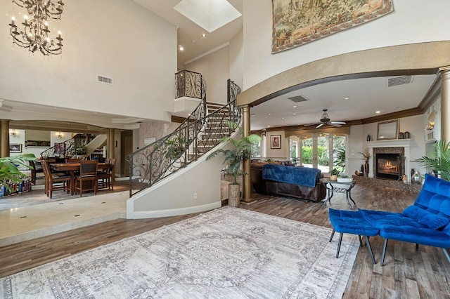 foyer entrance featuring a high end fireplace, ornamental molding, hardwood / wood-style flooring, a high ceiling, and ceiling fan with notable chandelier