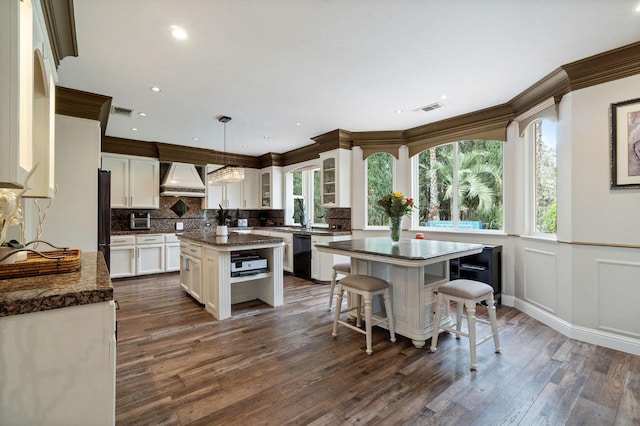 kitchen with decorative light fixtures, a center island, custom exhaust hood, dark hardwood / wood-style flooring, and black appliances