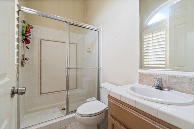 bathroom featuring vanity, a shower with shower door, and toilet