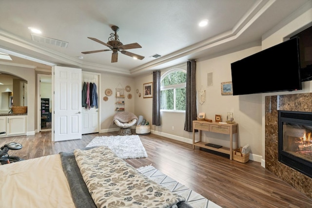 living room featuring a raised ceiling, light hardwood / wood-style floors, crown molding, a fireplace, and ceiling fan