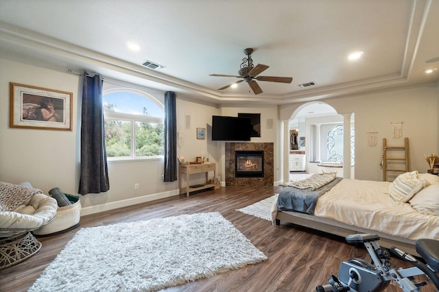 bedroom featuring ceiling fan, dark hardwood / wood-style flooring, a raised ceiling, and decorative columns