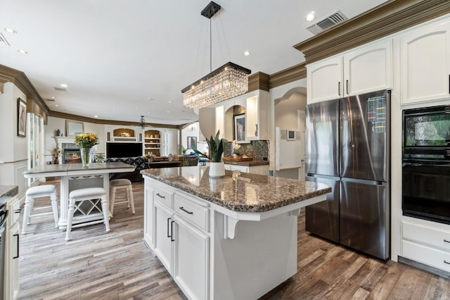 kitchen with a breakfast bar, white cabinetry, black appliances, and a notable chandelier