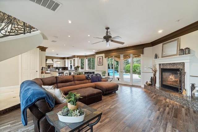 living room with french doors, ceiling fan, hardwood / wood-style flooring, a premium fireplace, and crown molding