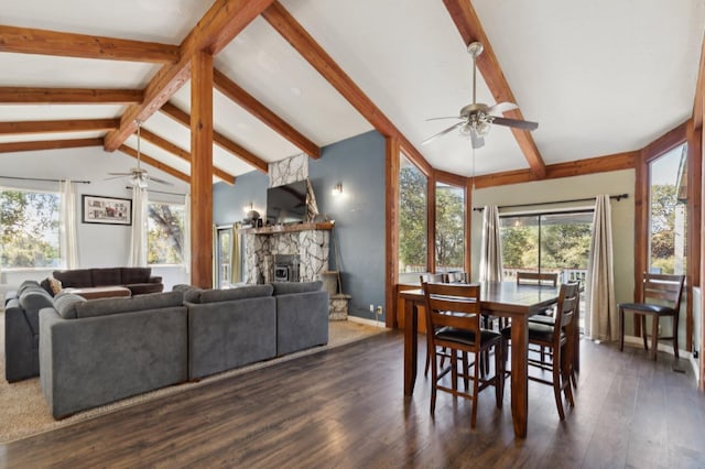 dining space with lofted ceiling with beams, a wealth of natural light, a stone fireplace, and dark hardwood / wood-style flooring