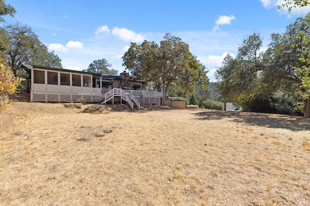 view of yard featuring a shed, a deck, and a sunroom