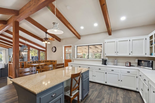 kitchen with light stone counters, dark hardwood / wood-style flooring, a center island, and white cabinets