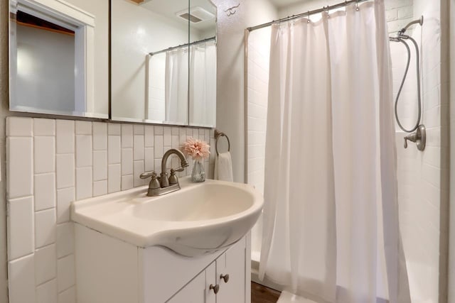 bathroom featuring vanity, curtained shower, and decorative backsplash