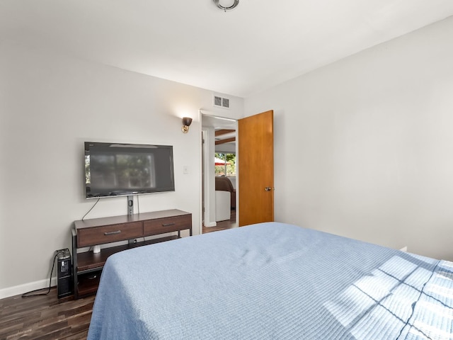 bedroom with visible vents, baseboards, and dark wood finished floors