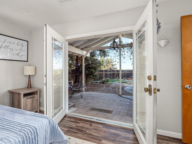 bedroom with wood finished floors, access to exterior, baseboards, visible vents, and lofted ceiling