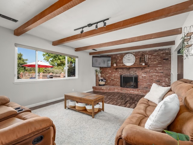 living room featuring wood finished floors, a brick fireplace, baseboards, visible vents, and beam ceiling