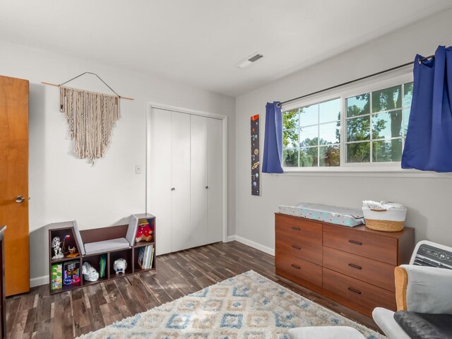 bedroom with baseboards, visible vents, wood finished floors, and a closet