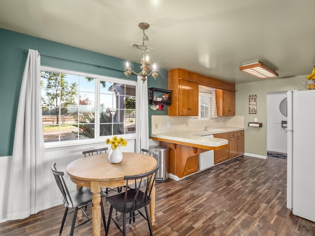 kitchen with decorative backsplash, freestanding refrigerator, light countertops, brown cabinets, and a sink