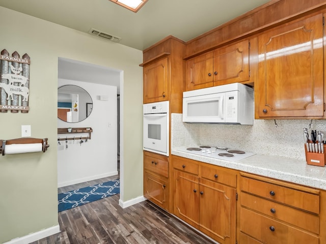 kitchen with tasteful backsplash, white appliances, light countertops, visible vents, and dark wood-type flooring