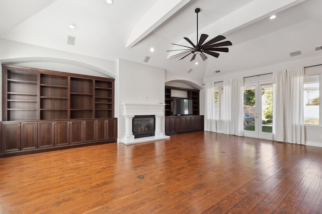 unfurnished living room with ceiling fan, vaulted ceiling with beams, and hardwood / wood-style floors