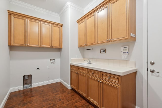 washroom with dark wood-type flooring, crown molding, washer hookup, and cabinets