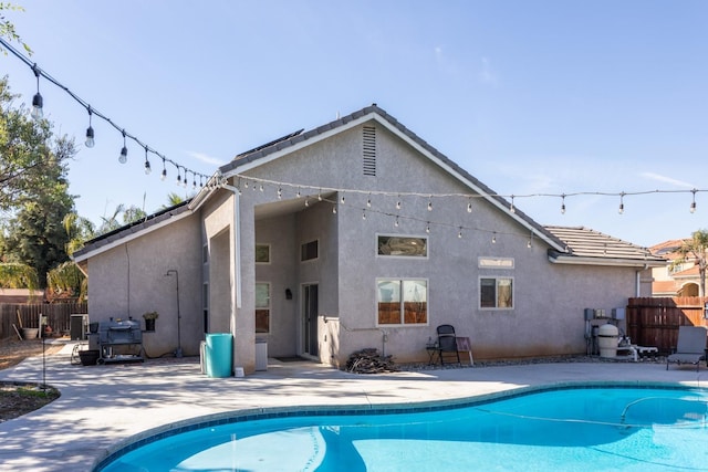 back of property with a fenced in pool, a patio area, fence, and stucco siding