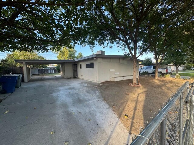 view of front of property featuring a carport, concrete driveway, and fence