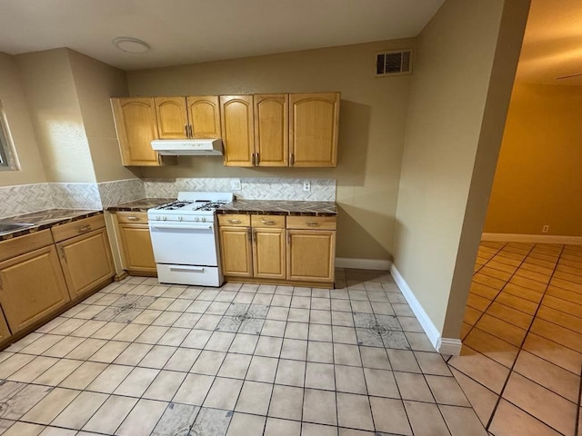 kitchen featuring light brown cabinetry, ceiling fan, white gas range, and light tile patterned floors